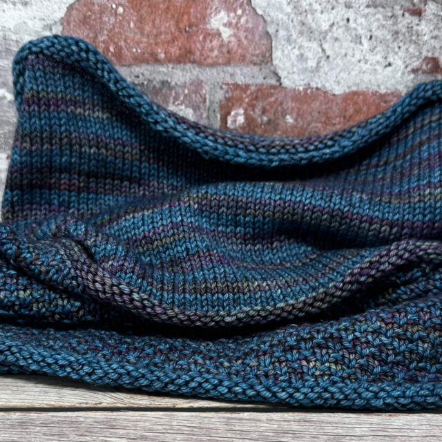 Versa Cowl open against brick wall.