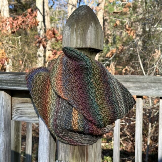 A photo of an infinity scarf wrapped around a fence post.