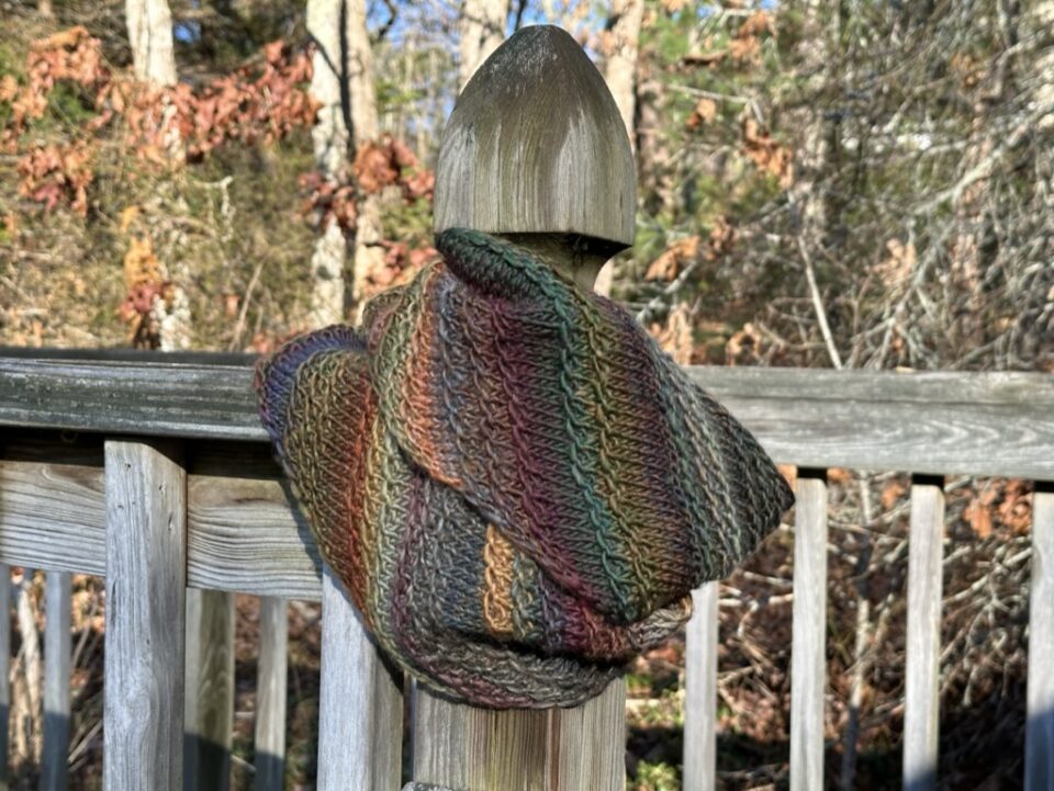 A photo of an infinity scarf wrapped around a fence post.